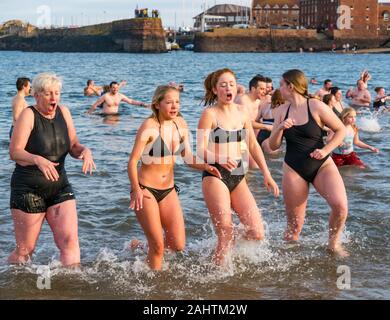 North Berwick, East Lothian, Reino Unido, 01 de enero de 2020. Loony Dook: Cientos de personas valientes las frías aguas del Firth of Forth para dar la bienvenida a 2020 en una tradición de Año Nuevo escocés, o Año Nuevo Dip. Un grupo de jóvenes mujeres que llevaban bikinis y una mujer de edad, salen de la sensación de mar muy frío