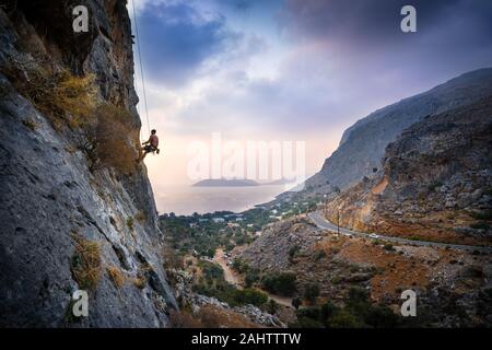 Hermoso atardecer paisaje con hombre bajando un Hard Rock suba en la isla de Kalymnos, Grecia. Foto de stock