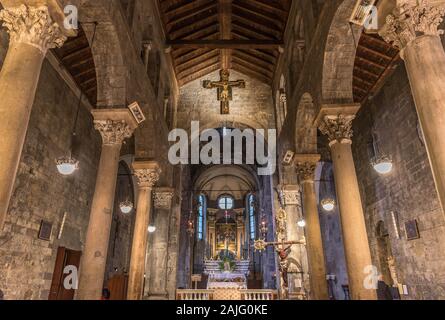 Genova, Genova, Italia: el interior de la iglesia románica de Chiesa di San Donato: paredes de piedra, techos de madera (vigas) de madera, Jesús crucificado (crucifijo)