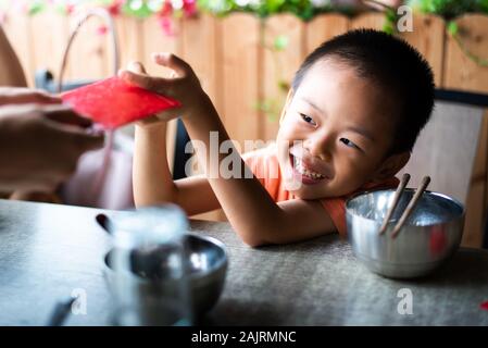 Niño chino recibe de bolsillo rojo sobre la mesa de comedor