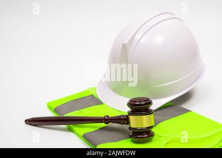 Un concepto jurídico laboral con seguridad sombreros, ropa de trabajo, y un juez martillo sobre un fondo blanco. Foto de stock