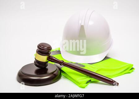 Un concepto jurídico laboral con seguridad sombreros, ropa de trabajo, y un juez martillo sobre un fondo blanco. Foto de stock