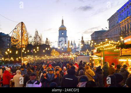 KIEV, Ucrania - Enero 06, 2020: Las personas que asistan a los mercados de Navidad y Año Nuevo en el casco antiguo de la ciudad de Kiev, con la Catedral de Sofía en el fondo