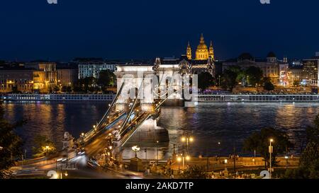 Vista nocturna de monumentos arquitectónicos y la Basílica Saint Stephens Cadena Szechenyi Puente sobre el río Danubio en Budapest, Hungría. Foto de stock