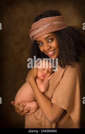 Madre joven etíope sostiene a su bebé de 7 días de edad poco contra un fondo oscuro