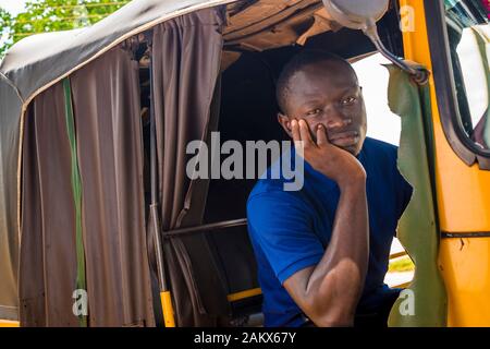 joven africano mirando y sintiéndose triste sentado en un rickshaw Foto de stock