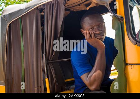 joven africano mirando y sintiéndose triste sentado en un rickshaw Foto de stock