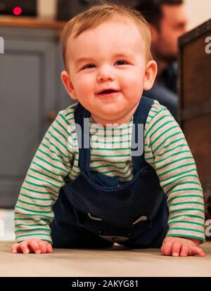 7 mes de edad Baby Boy felizmente arrastrándose por salón piso Foto de stock