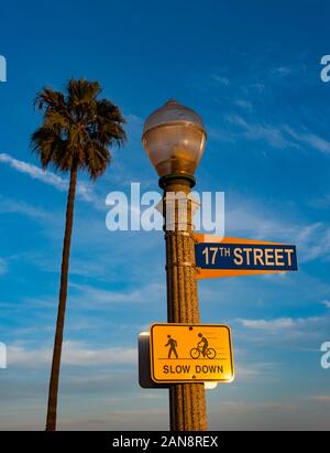 Newport Beach Street firmar y lámpara iluminada por la luz del atardecer, 17th street firmar con firmar la ruta peatonal y ciclista Foto de stock
