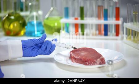 Trabajador de laboratorio inyectar medicamento en muestra de carne, análisis de gripe porcina africana Foto de stock
