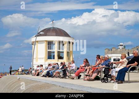 Los ancianos se relajan bajo el sol junto al pabellón de música situado en el paseo marítimo de la playa norte de la isla Borkum Foto de stock