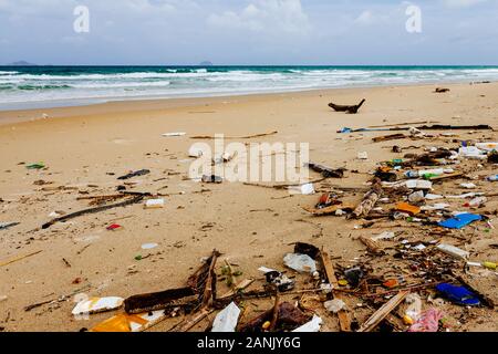 Basura en la orilla de una hermosa playa del mar, la contaminación ambiental, un montón de botellas de plástico, espuma de poliestireno, problema ambiental. Olas moviendo Foto de stock