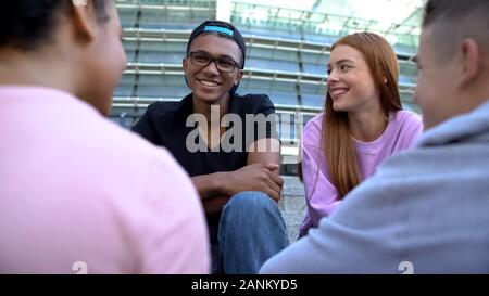 Las parejas adolescentes multiétnicos comunicando al aire libre, pasar tiempo juntos, relajarse