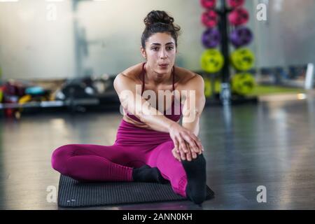 Mujer joven haciendo ejercicios de estiramiento en una estera del yoga