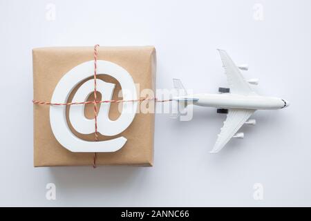 Plano de laicos envoltorio con correo electrónico símbolo y modelo de avión sobre fondo blanco. Logística de transporte transporte mínimo concepto creativo. Foto de stock