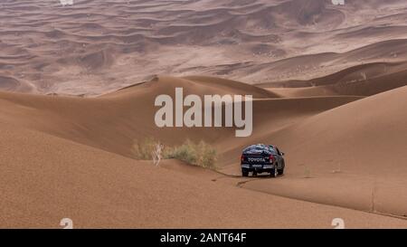 toyota hulux revo escalando por una duna de arena en un clima lluvioso en dasht e lut o desierto del sahara Foto de stock
