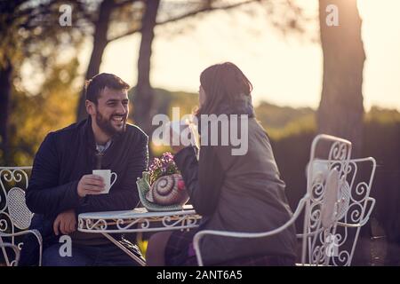 Sonriendo el hombre y la mujer en el amor y en la tarde disfrutar bebiendo café