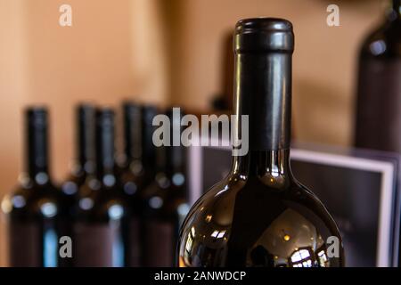 Una botella de vino de vidrio ámbar, verde oscuro, el acabado superior sin junta, el cuello y el hombro de cerca, el enfoque selectivo vista contra un montón de botellas de vinos Foto de stock