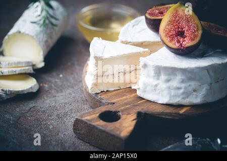 Cabra fresco queso brie con trufa blanca y el molde sobre un plato de queso con higos y miel Foto de stock