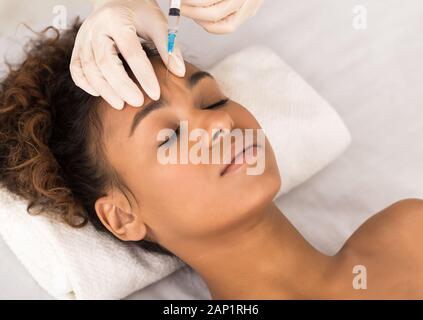 Concepto de cosmetología. Mujer Afro obteniendo inyección de belleza Foto de stock