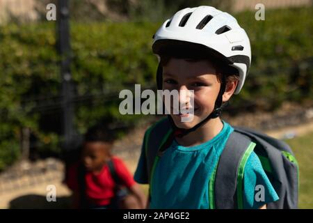 Niño escolar que lleva un casco de ciclismo y que monta en bicicleta Foto de stock