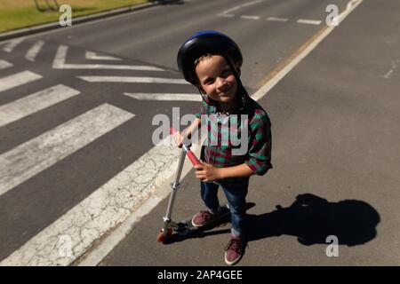 Niño escolar que lleva un casco de ciclismo en un cruce peatonal Foto de stock