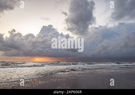 Tres nubes de tormenta sobre el mar mientras el sol se pone en el horizonte