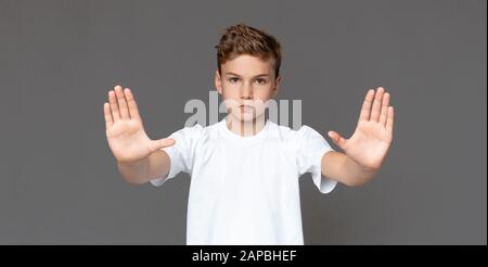 Adolescente haciendo un gesto de parada sobre fondo gris Foto de stock