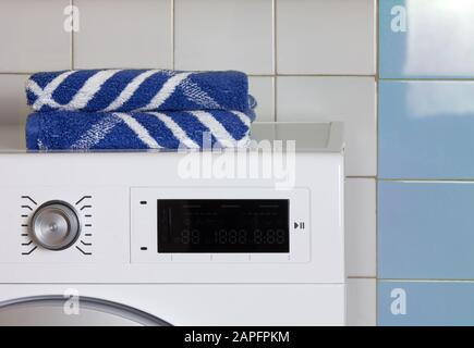 Dos toallas azules en la parte superior de una lavadora en una sala de lavandería Foto de stock