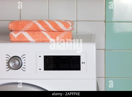 Dos toallas de naranja en la parte superior de una lavadora en una sala de lavandería Foto de stock