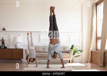 Niña pequeña hacer ejercicio en casa. Soporte de mano con presión. Lindo  niño está de pie en las manos cerca de un alféizar de madera interior. Modelo  femenino de pelo oscuro en