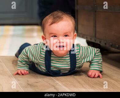 7 mes de edad Baby Boy felizmente arrastrándose por salón piso Foto de stock