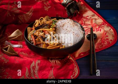 El tradicional Buda chino Delight STIR Fry para año Nuevo se sirve en un tazón negro sobre la tradicional cubierta de tela roja Foto de stock