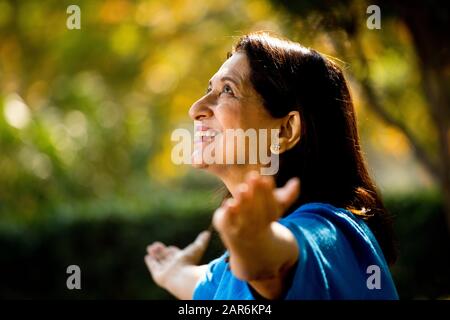 Mujer mayor con brazos extendidos en el parque