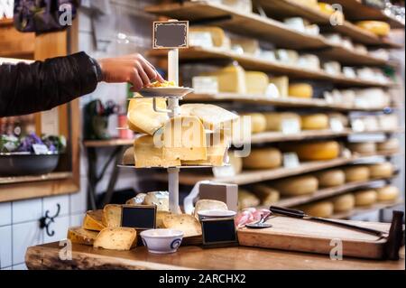 Mujer degustación y elección de queso orgánico holandés en la tienda con docenas de tipos de queso. Amsterdam, Holanda