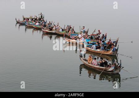 Los turistas están esperando la puesta de sol en canoas en Taung Tha Man Lake, Mandalay