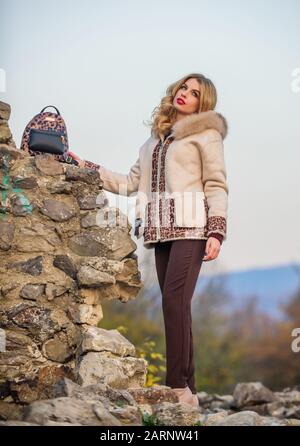 Golpe de temporada. Mantente cálido y moderno. Mujer llevar pelaje. Ropa de  invierno. Armario para clima frío. Chica se encuentra cerca de ruinas de  piedra. Elegante abrigo chic. Abrigo de piel de