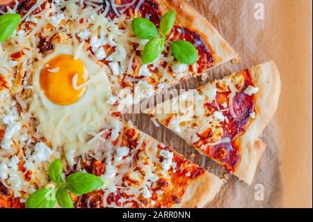 Tiro de pizza con huevo, queso y hierbas. Escena rústica y luz dramática. Foto de stock