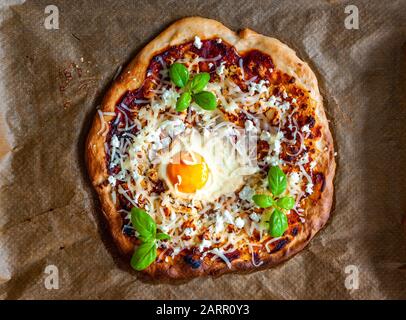 Un golpe de pizza con huevo, queso y hierbas. Escena rústica y luz dramática. Foto de stock