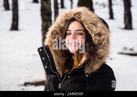 Retrato de una joven feliz y hermosa adolescente vestida con ropa de invierno de pie en la nieve y sonriendo. Montañas de Troodos en Chipre