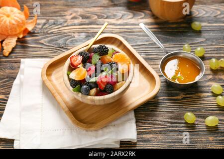 Cuenco con sabrosa ensalada de frutas en mesa de madera Foto de stock