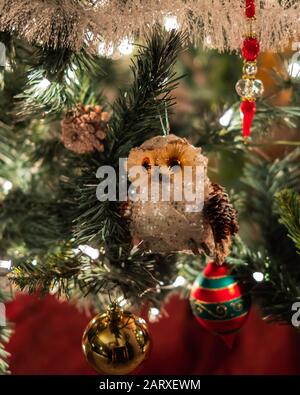 Vista de primer plano de un árbol de Navidad artificial decorado con ornamentos de búho y pelota. Foto de stock