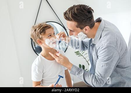 Padre y su hijo pequeño afeitándose en el baño Foto de stock