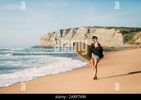 Mujer sosteniendo las tablas de surf en la playa Foto de stock