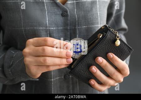 Mujer sacando bitcoin de la cartera, closeup Foto de stock