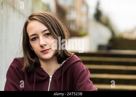 Retrato de una niña universitaria de 17 años sentada en el entrenamiento en una escalera