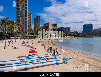 Waikiki, HI - 19 de enero de 2020: Canoas tradicionales frente a la torre Rainbow del Hilton en la playa Waikiki en Hawai Foto de stock