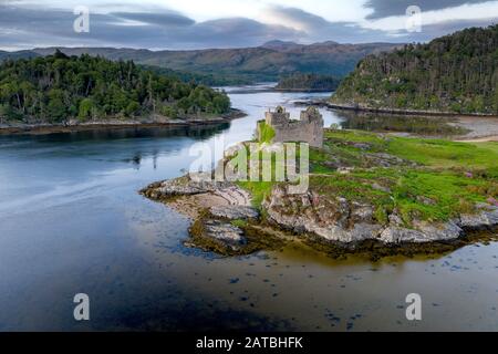 Tiro aéreo de drone del Castillo Tioram, es un castillo en ruinas que se encuentra en la isla de marea Tioram Eilean en Loch Moidart, Lochaber, Highland, Escocia. YO Foto de stock