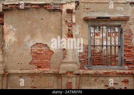 pared de hormigón renderizado con ladrillo rojo expuesto y celda de cárcel de madera como ventana Foto de stock