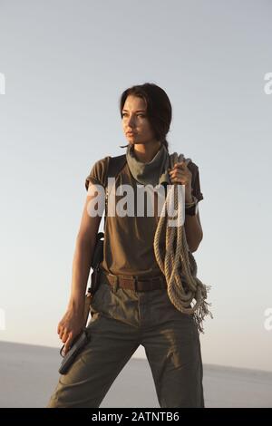 Retrato de mujer joven con arma en ropa militar al aire libre